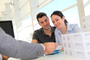 Couple in real-estate agency signing property loan contract